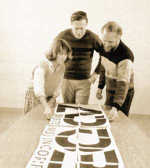 Чарльз Гешке, Джон и Марва Уорнок рассматривают распечатанный логотип