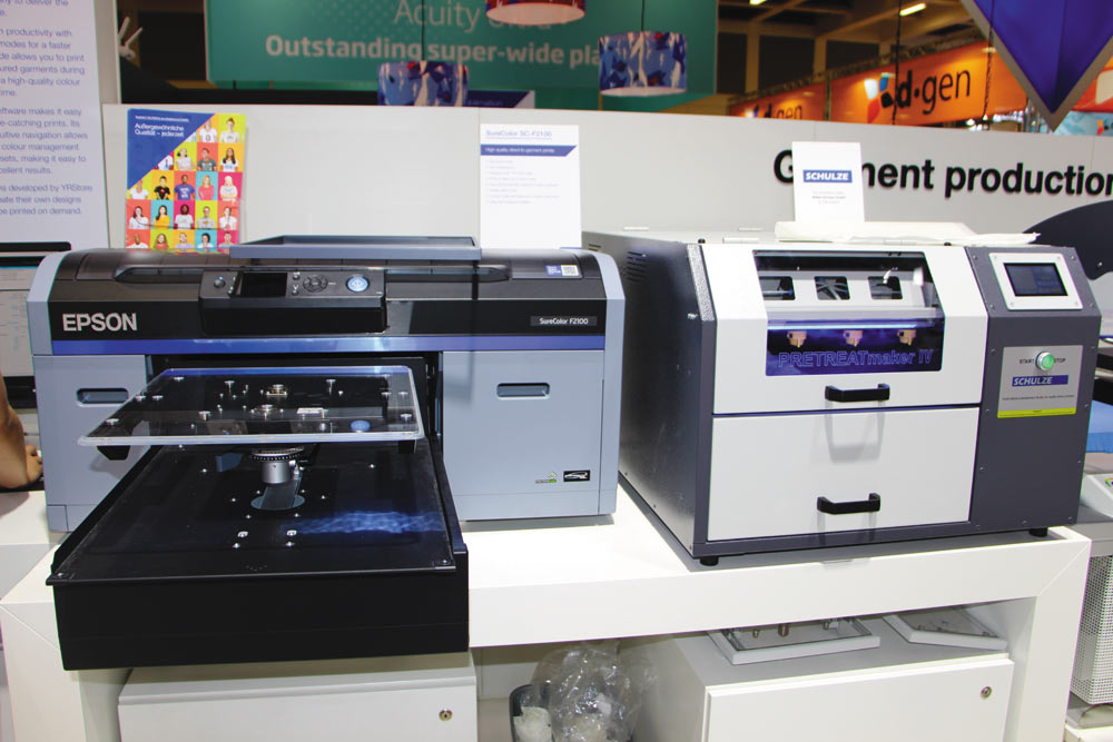 SureColor SC-F2100 демонстрировался в паре с Schulze PRETREATmaker IV — автоматической машиной для нанесения грунтовки на текстильные изделия, что требуется при печати белыми водорастворимыми красками на темных изделиях из натуральных и смесевых тканей, а также при печати на синтетике