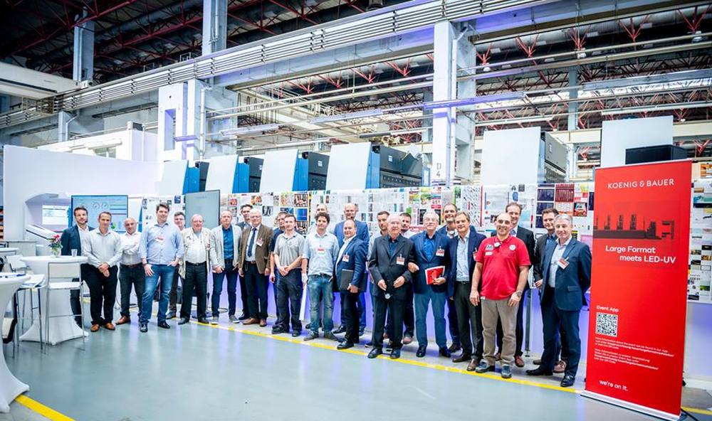 Посетители специального мероприятия перед демонстрационной печатью. На галерее можно увидеть лист из каждого из 13 заказов.